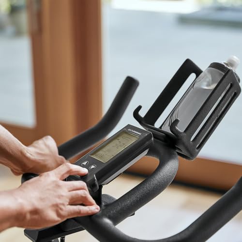Person using a digital display on an exercise bike indoors.