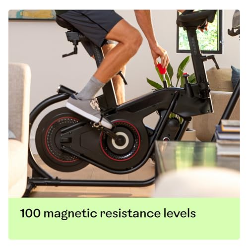 Person using a stationary bike with text '100 magnetic resistance levels' in a home setting.