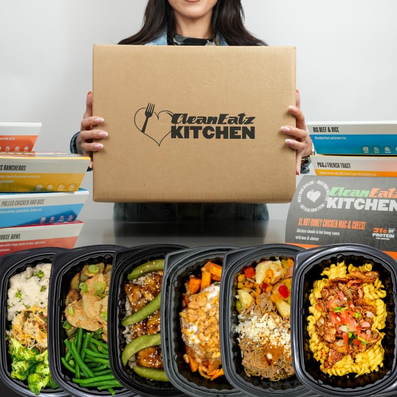 Person holding a CleanEatz Kitchen box with prepared meals displayed below.