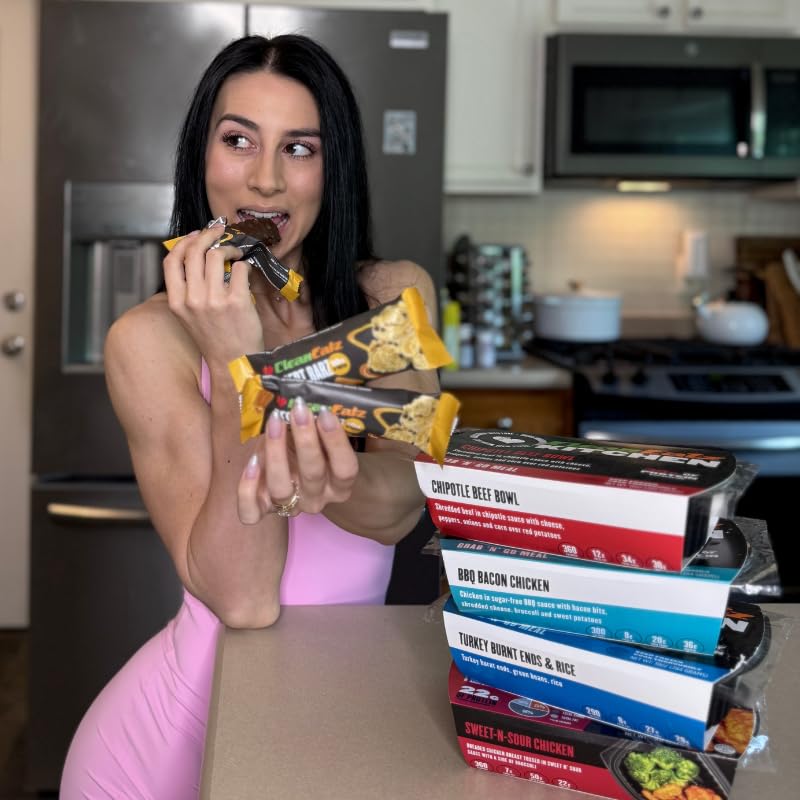 Woman in a kitchen holding a package of food, with a stack of similar packages on the counter.