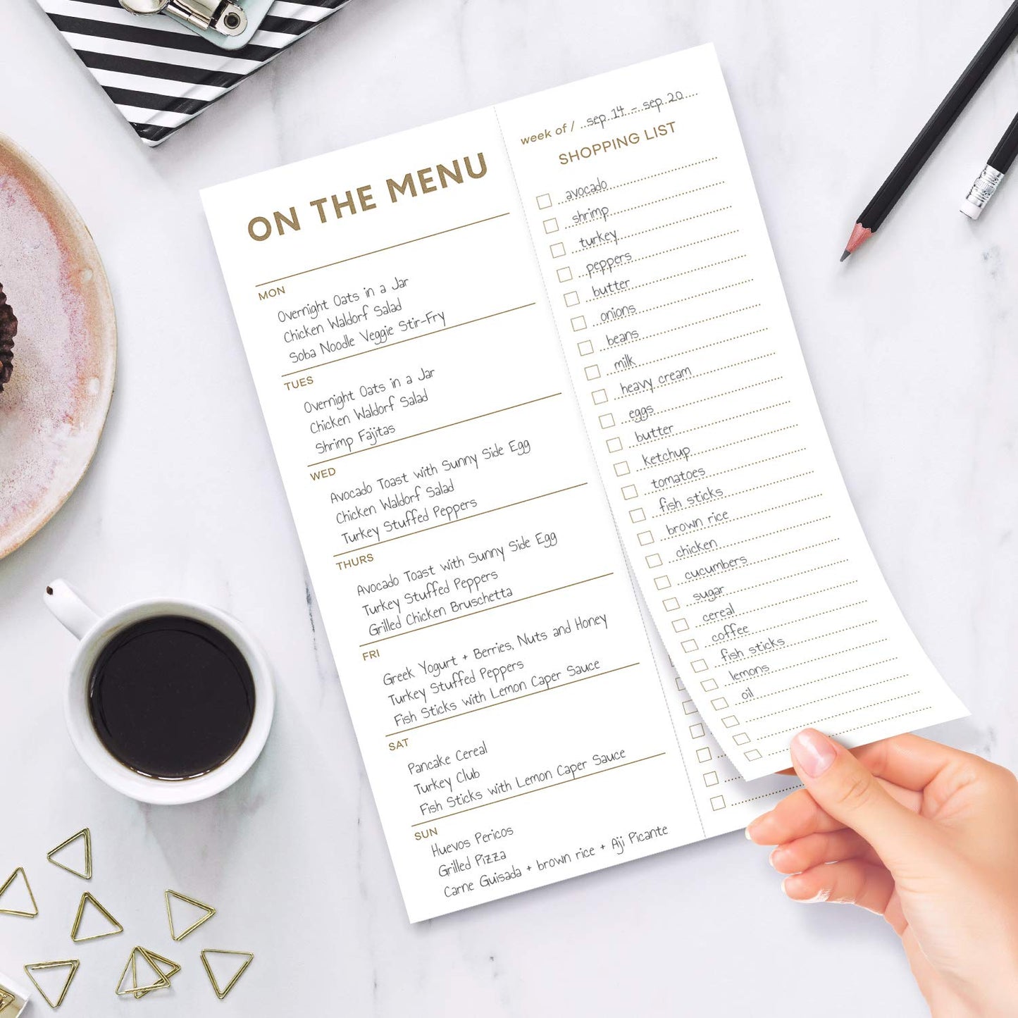 Menu and shopping list on a table with a cup of coffee and pencils.