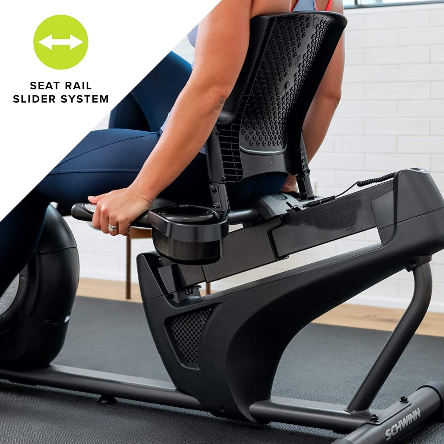 Person using a Schwinn exercise bike with a seat rail slider system feature highlighted.