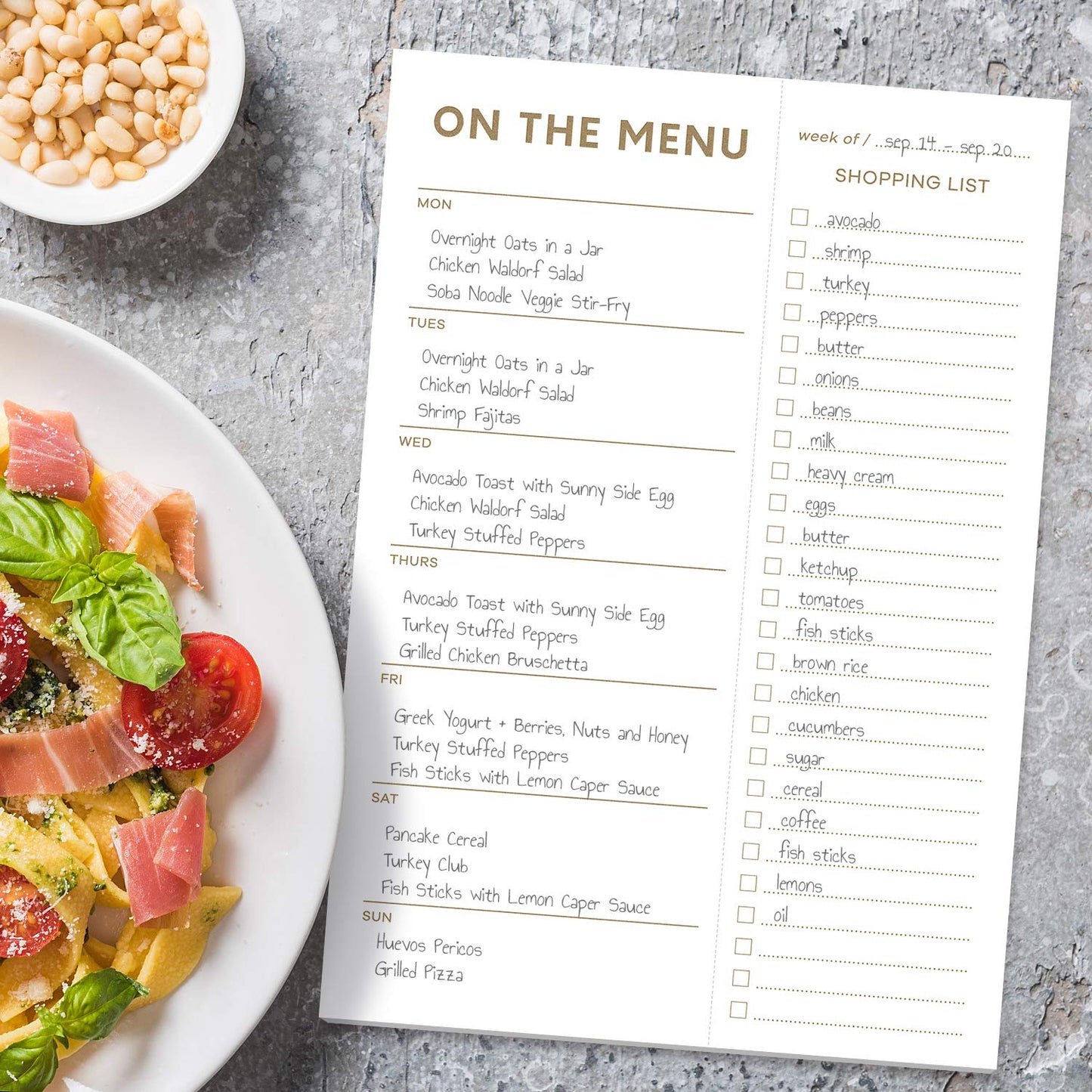 Menu planning sheet with a plate of pasta and vegetables on a gray surface