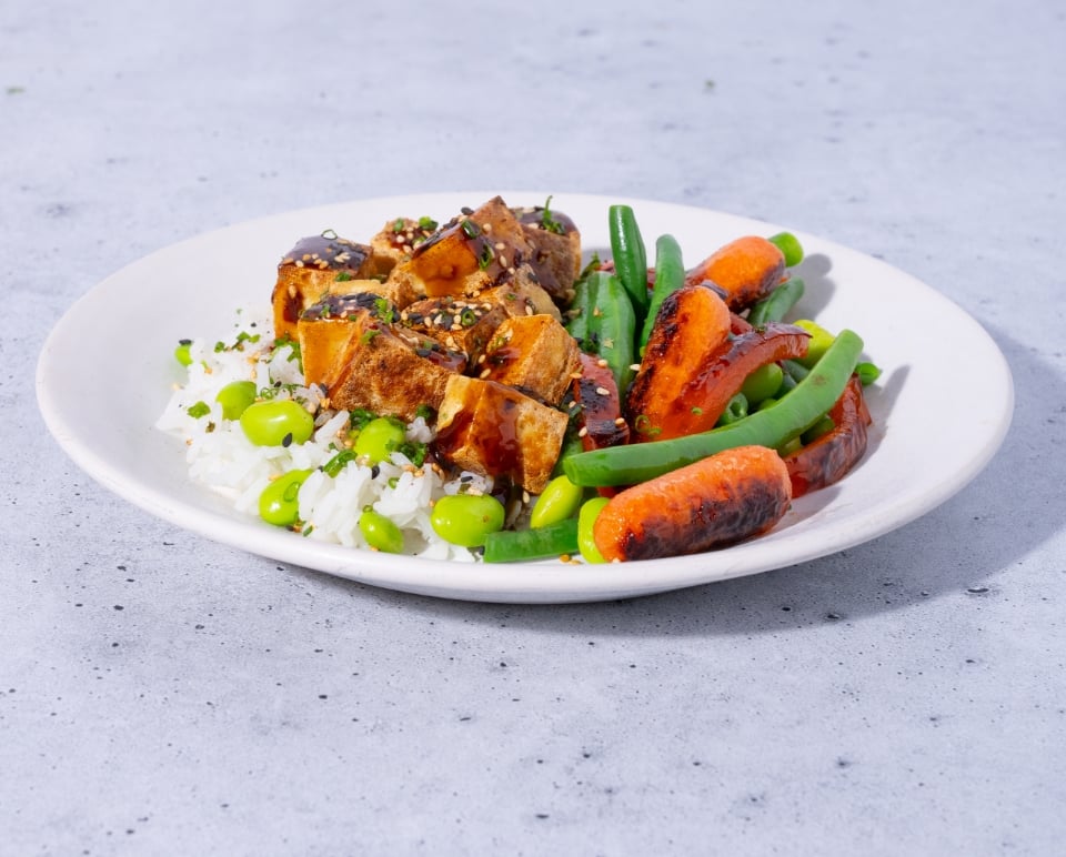Plated dish with rice, tofu, and vegetables on a light gray background