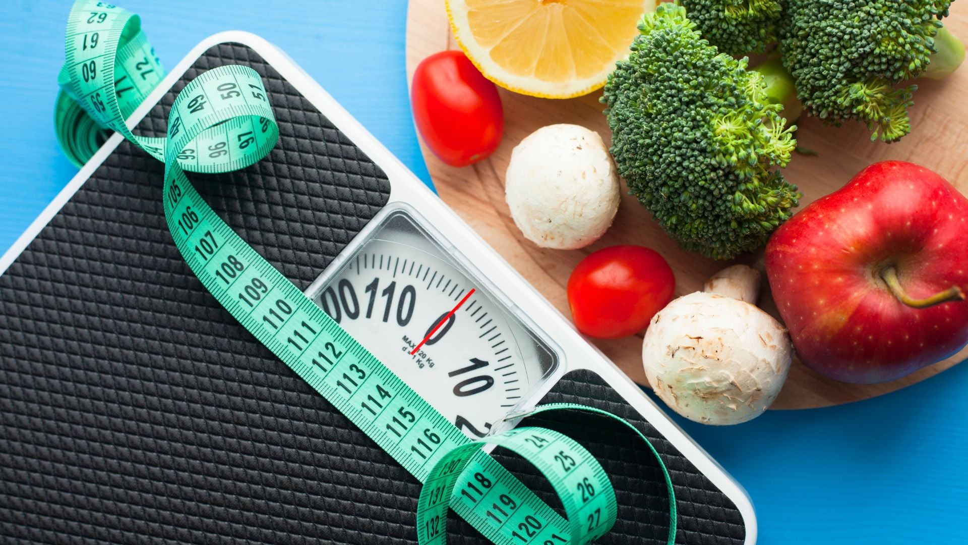 Weight scale with measuring tape, fruits, and vegetables on a blue background