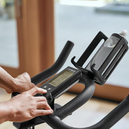 Person using a digital display on an exercise bike indoors.