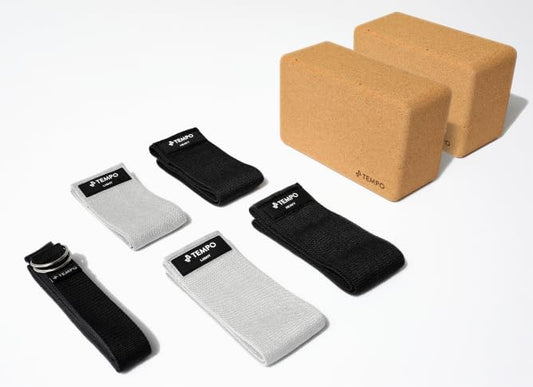 Set of yoga accessories including blocks, straps, and a device on a white background