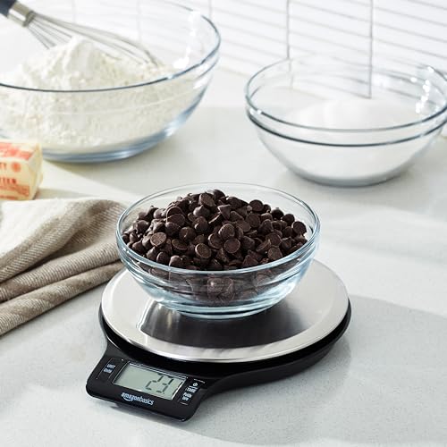 Bowl of chocolate chips on a digital kitchen scale with ingredients in the background