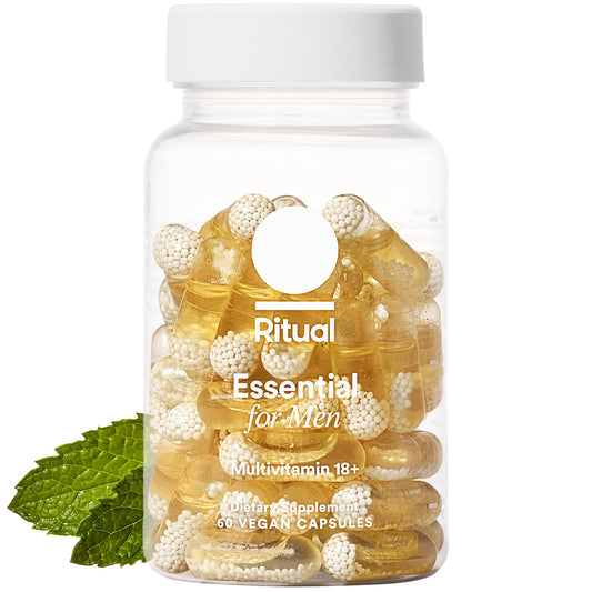 Multivitamin supplement bottle with capsules and a leaf on a white background