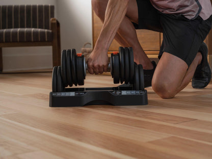 Person adjusting a dumbbell set on a wooden floor
