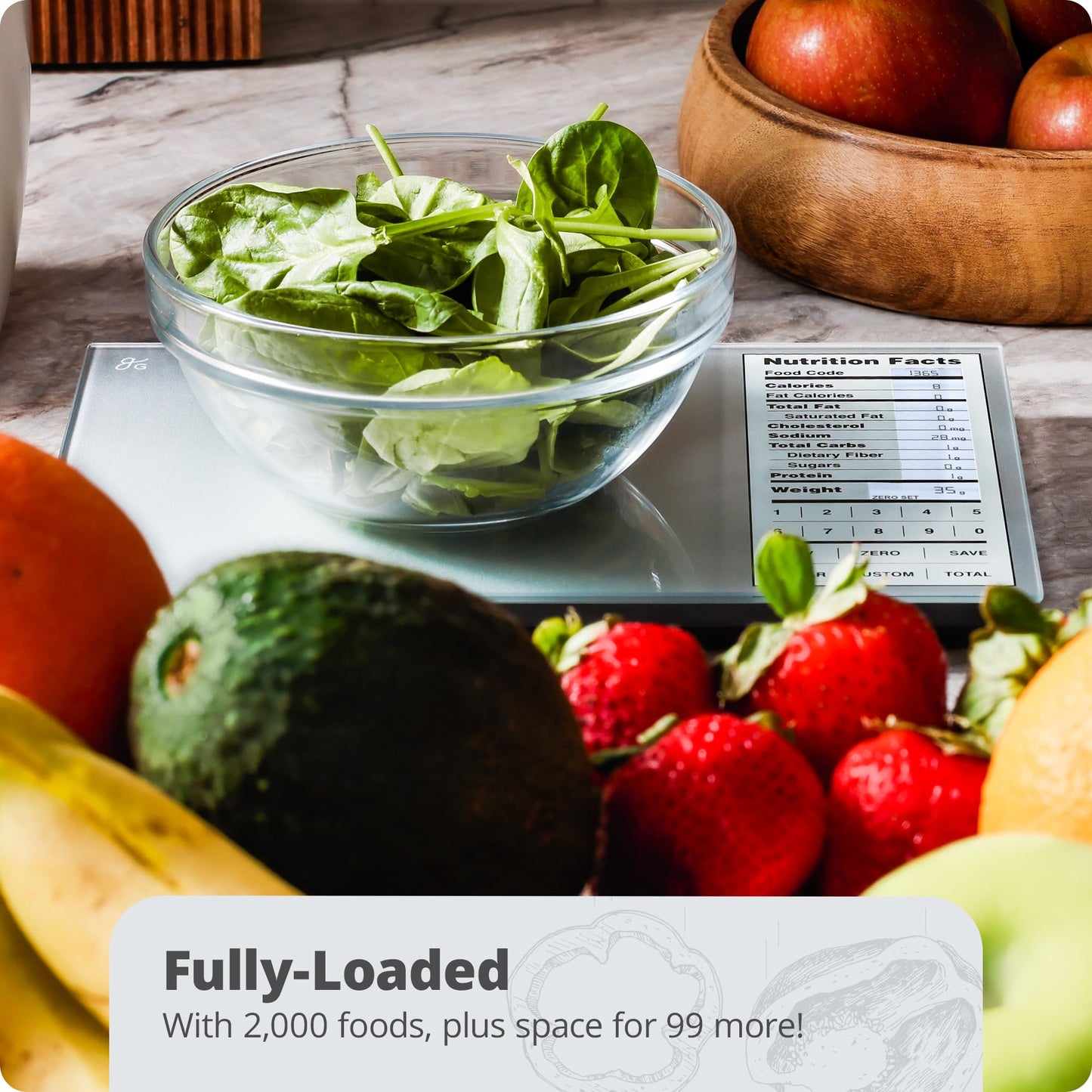 Fruits and vegetables on a kitchen scale with a nutrition facts label, including spinach, apples, strawberries, and an avocado.