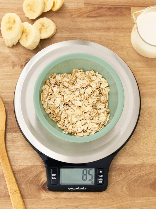 Digital kitchen scale with a bowl of oats on a wooden surface