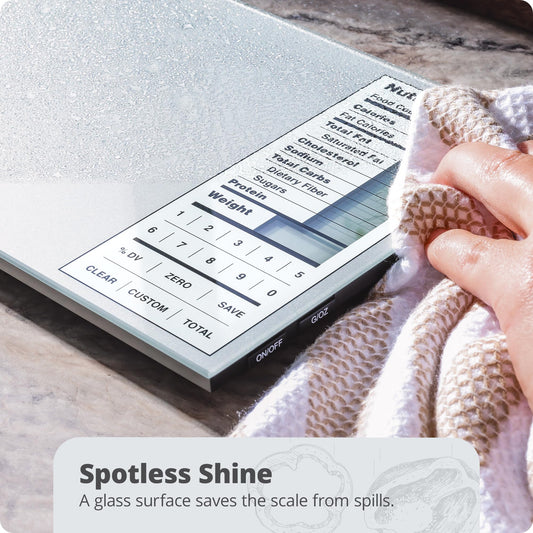 Digital kitchen scale with a glass surface being wiped by a hand, on a marble countertop.