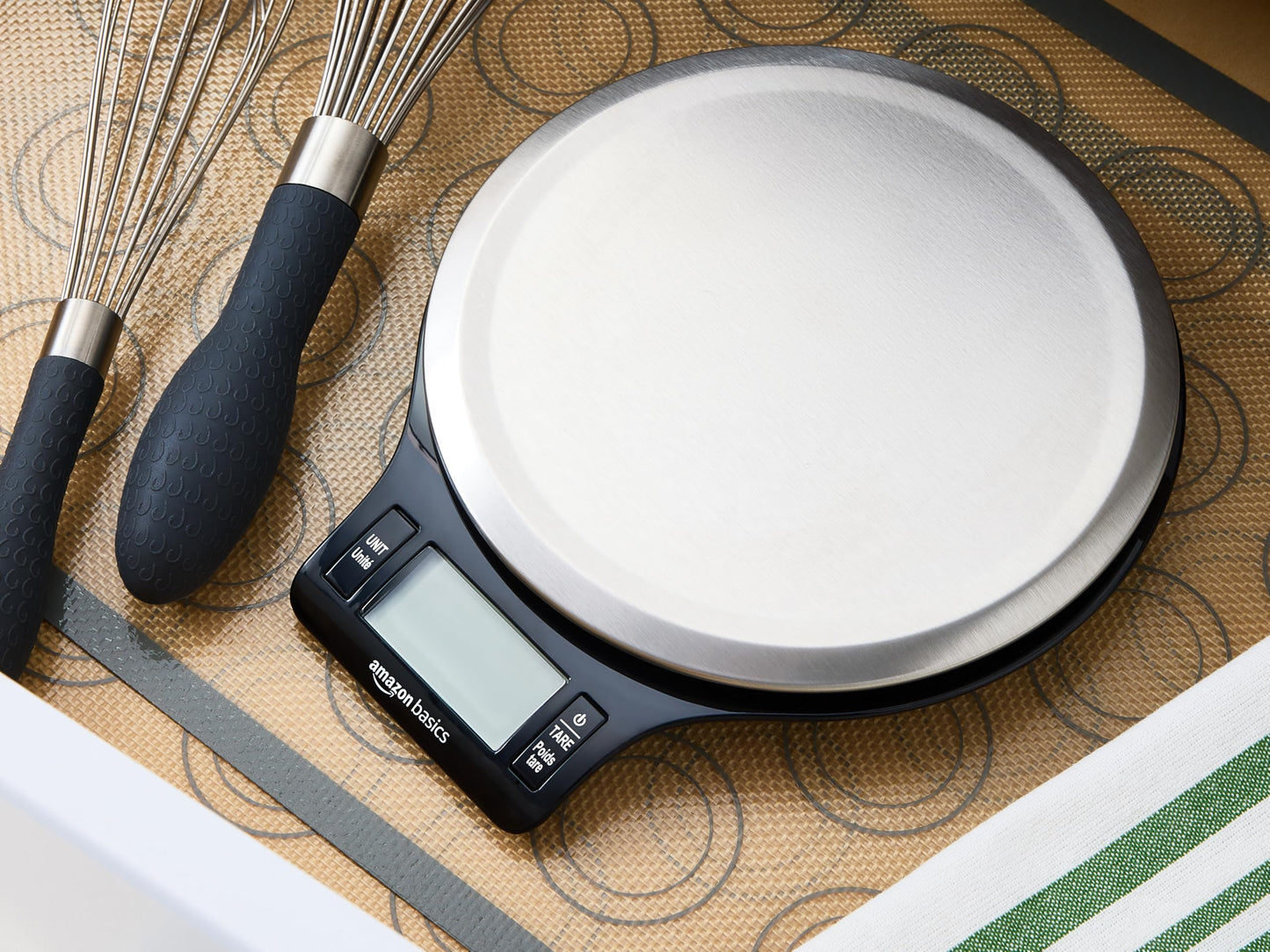 Digital kitchen scale with whisk and spatula on a patterned surface