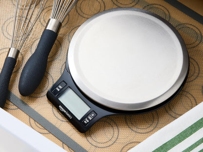 Digital kitchen scale with whisk and spatula on a patterned surface