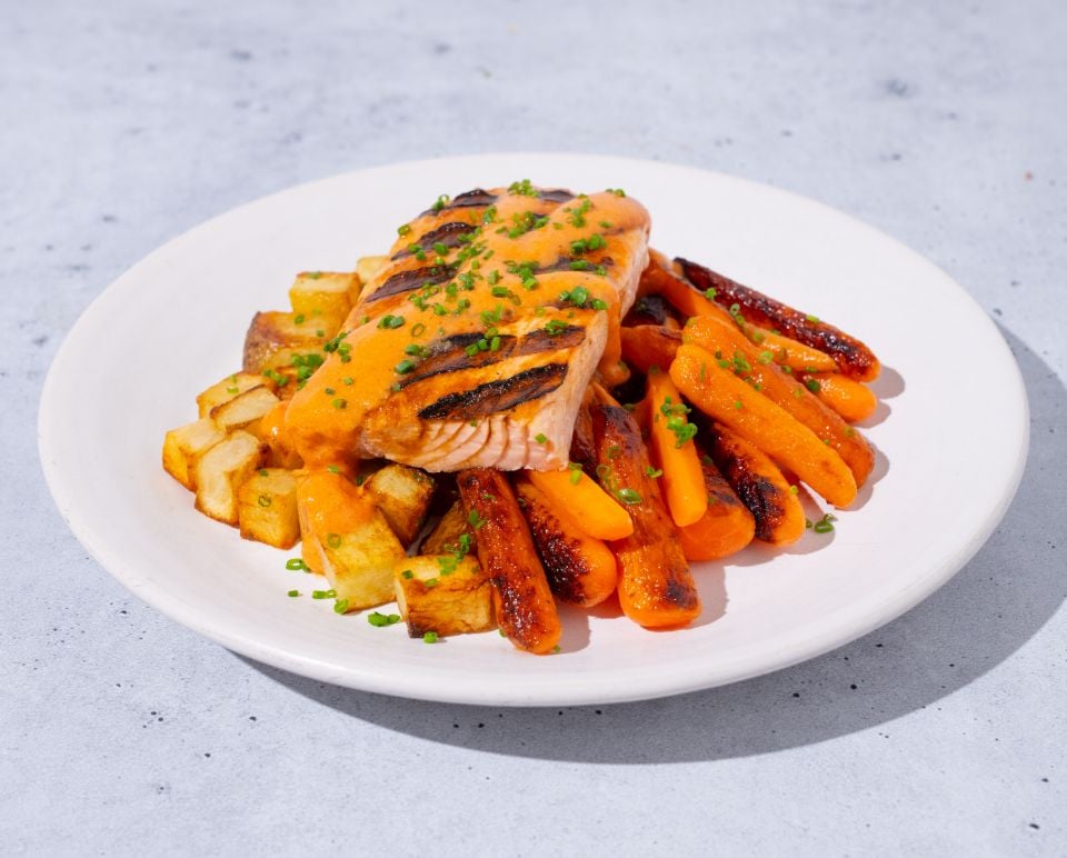 Plated dish with salmon, carrots, and potatoes on a light gray background