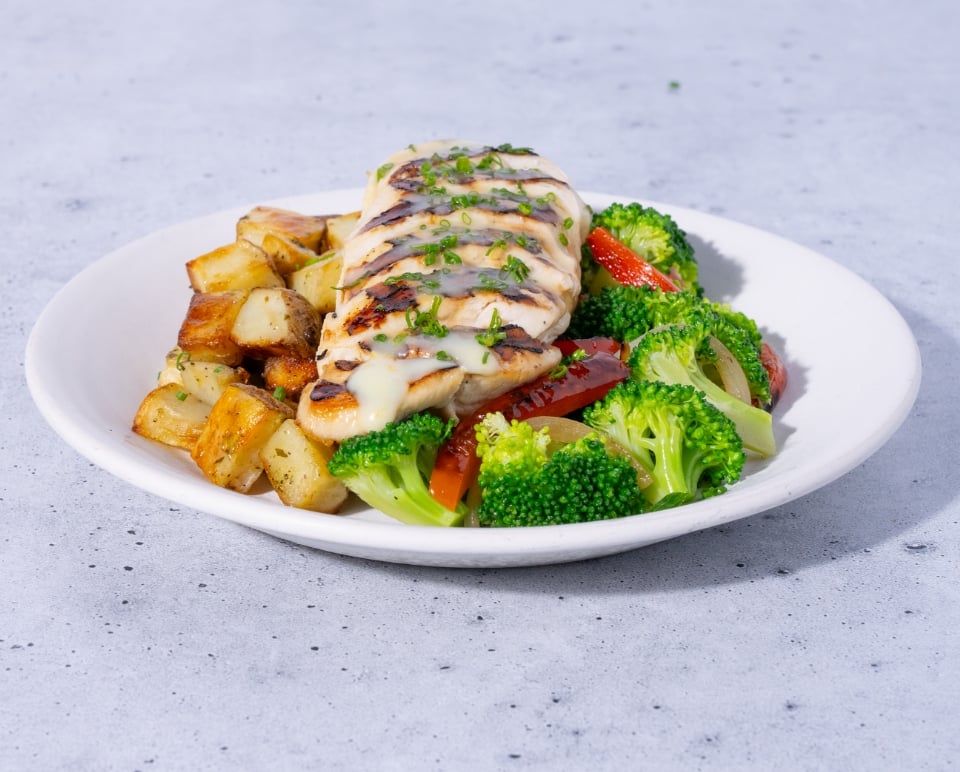 Plated dish with chicken, broccoli, and potatoes on a gray surface
