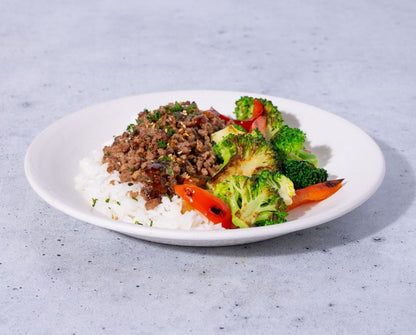 Plate of food with rice, ground meat, and broccoli on a gray surface