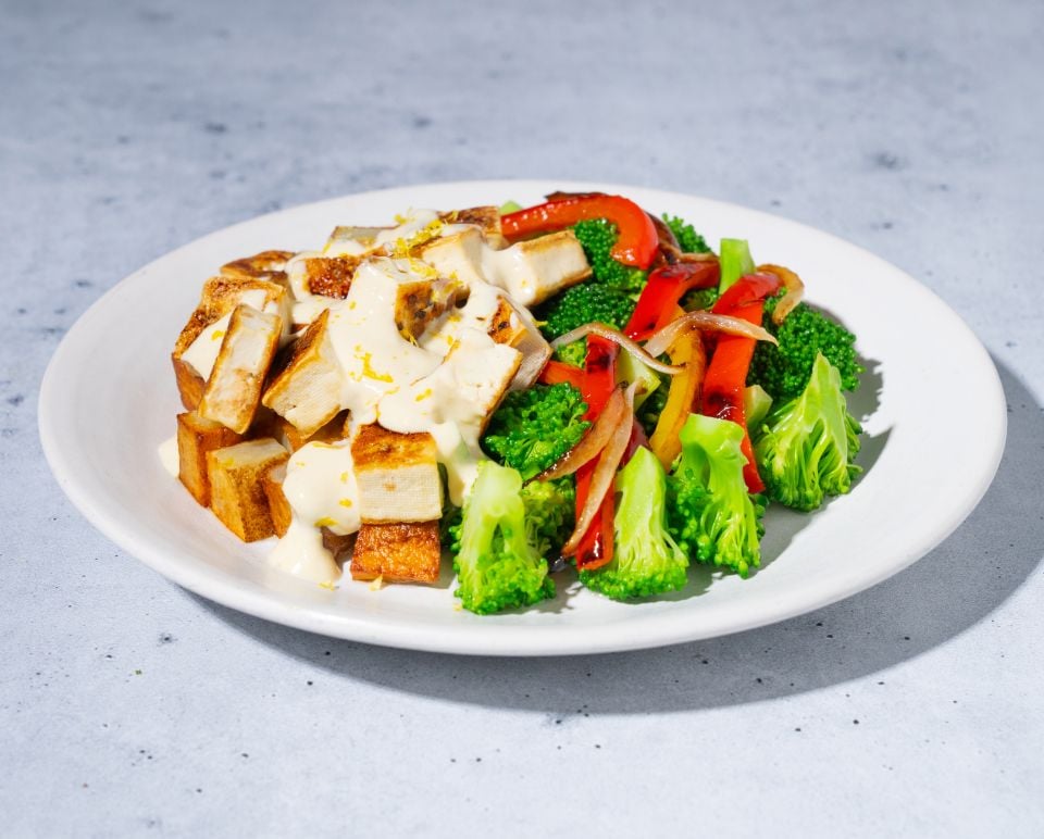 Plated dish with tofu, broccoli, and red bell peppers on a gray background