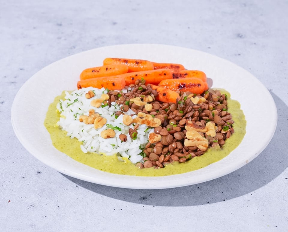 Plated dish with rice, lentils, and carrots on a light gray background