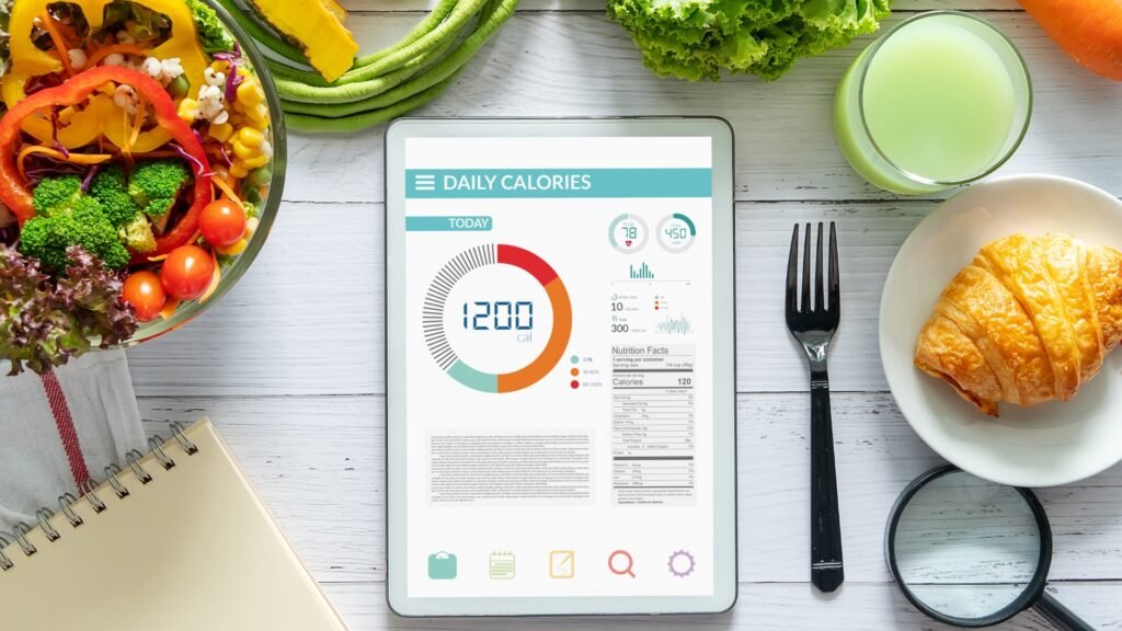 Calorie tracking and food journaling for healthy weight management. Digital tablet showing daily calorie tracking alongside healthy foods and a food journal