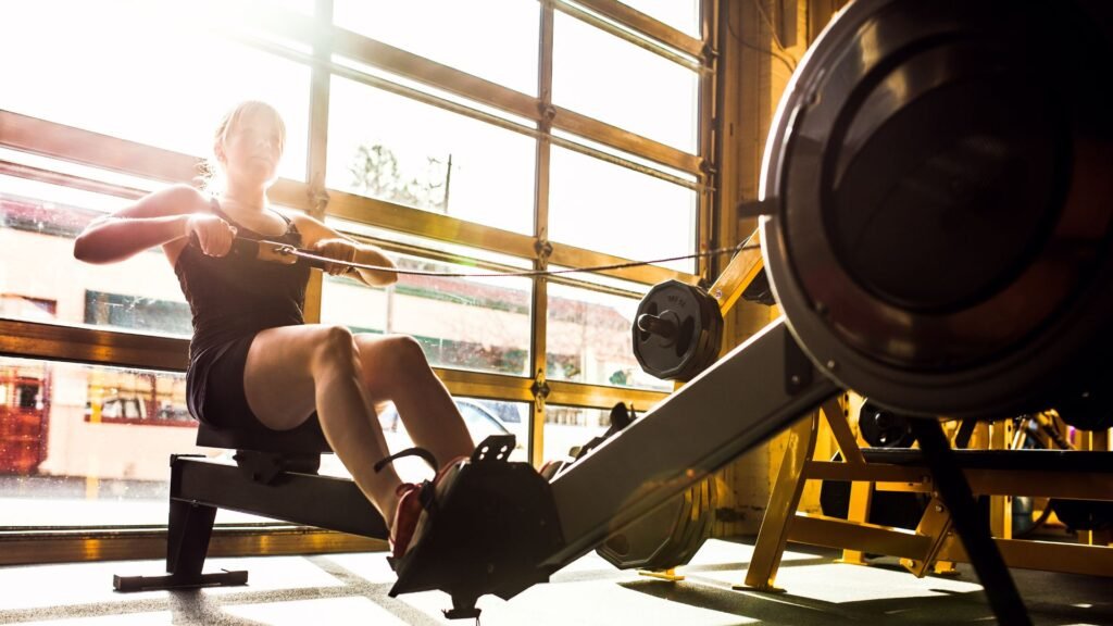 Woman training on a rowing machine in a sunlit gym
