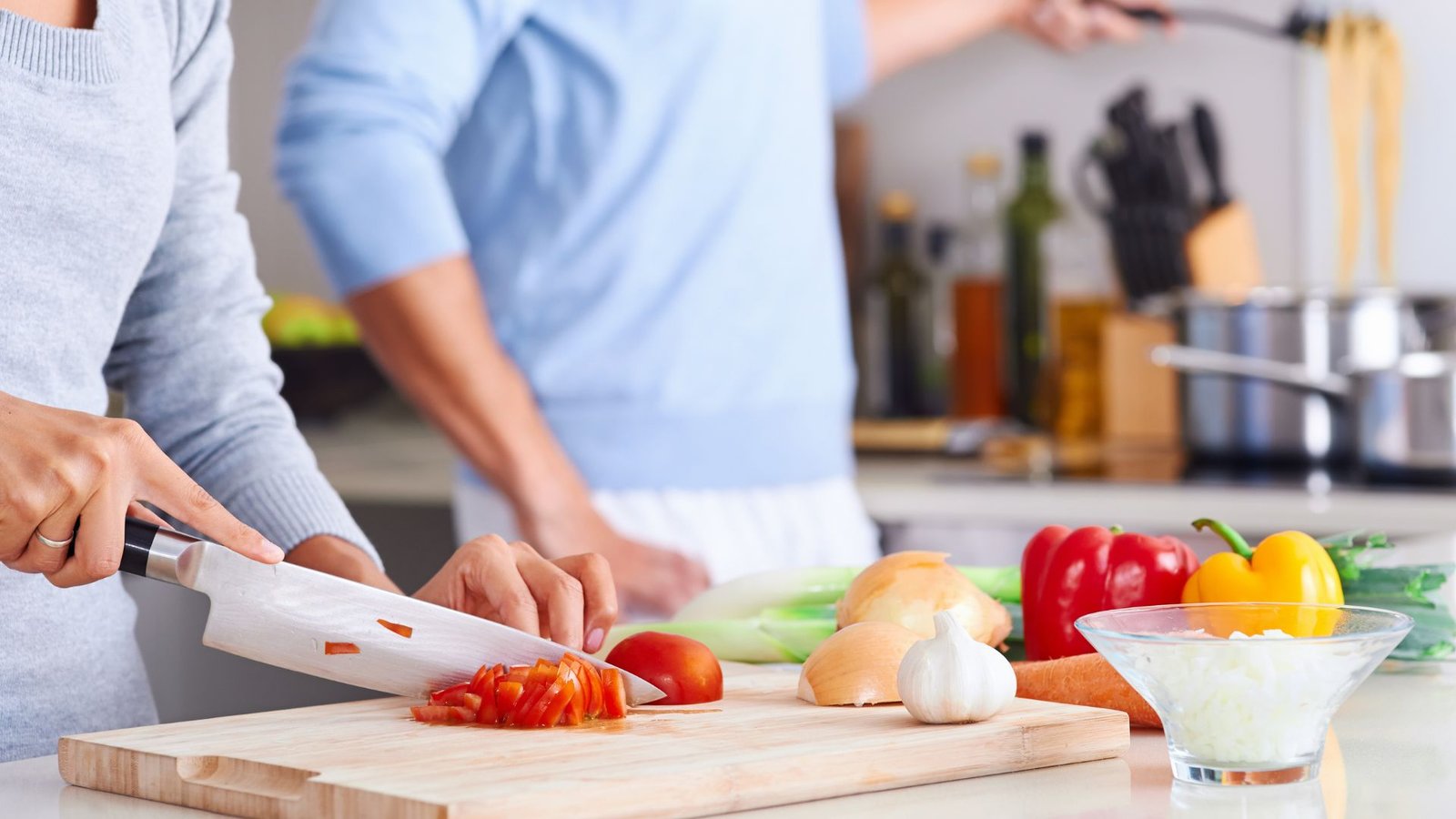 Couple preparing a healthy home-cooked meal with fresh vegetables on a kitchen counter