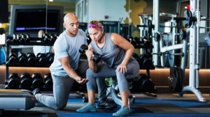 Personal trainer coaching a woman with dumbbells in a gym