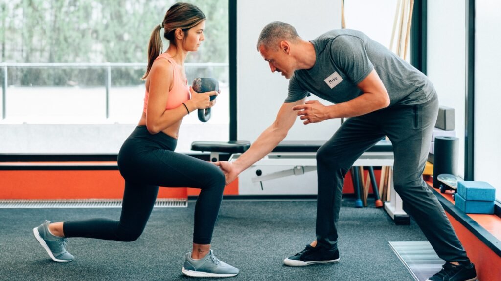 Personal trainer coaching client on proper lunge technique in gym