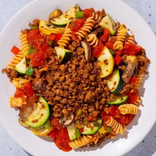 Trifecta vegan pasta bowl with plant-based crumbles, zucchini, mushrooms, and tomato sauce