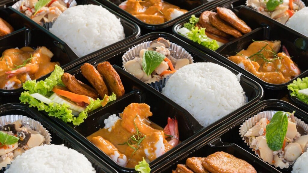 Assorted pre-packaged healthy meals with rice, vegetables, and lean proteins in black meal containers