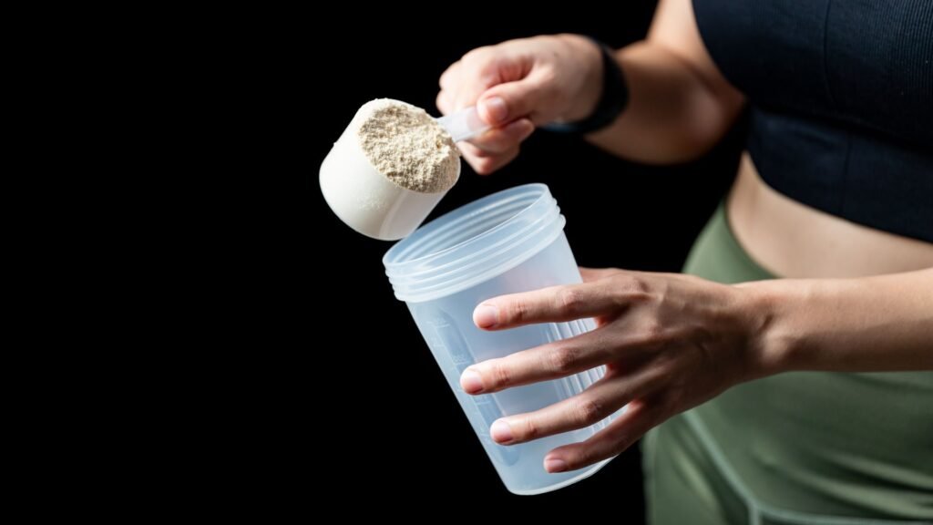 Person pouring protein powder into shaker bottle