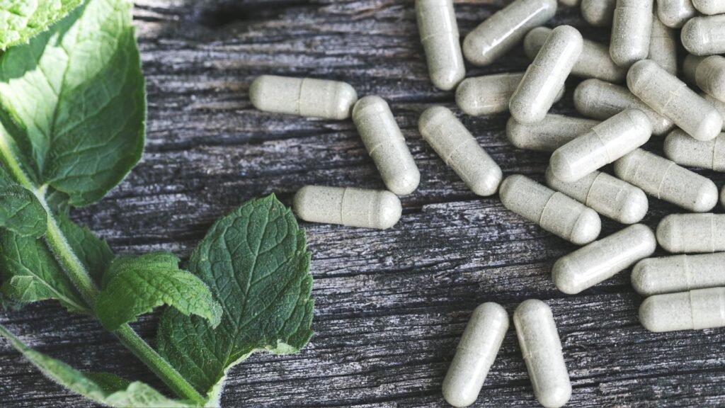 Herbal supplement capsules with mint leaves on a rustic wooden background