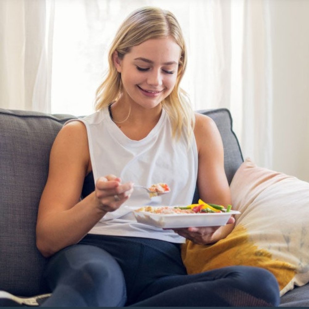 Woman enjoying a healthy Trifecta meal at home on the couch