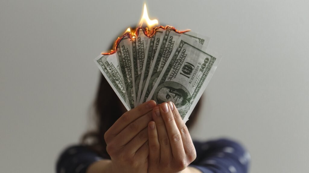 Person holding burning cash to symbolize the hidden long-term costs of weight loss drugs