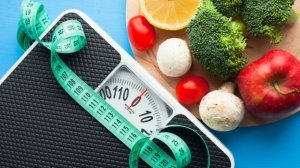 Weight loss tools including a bathroom scale, tape measure, and healthy foods